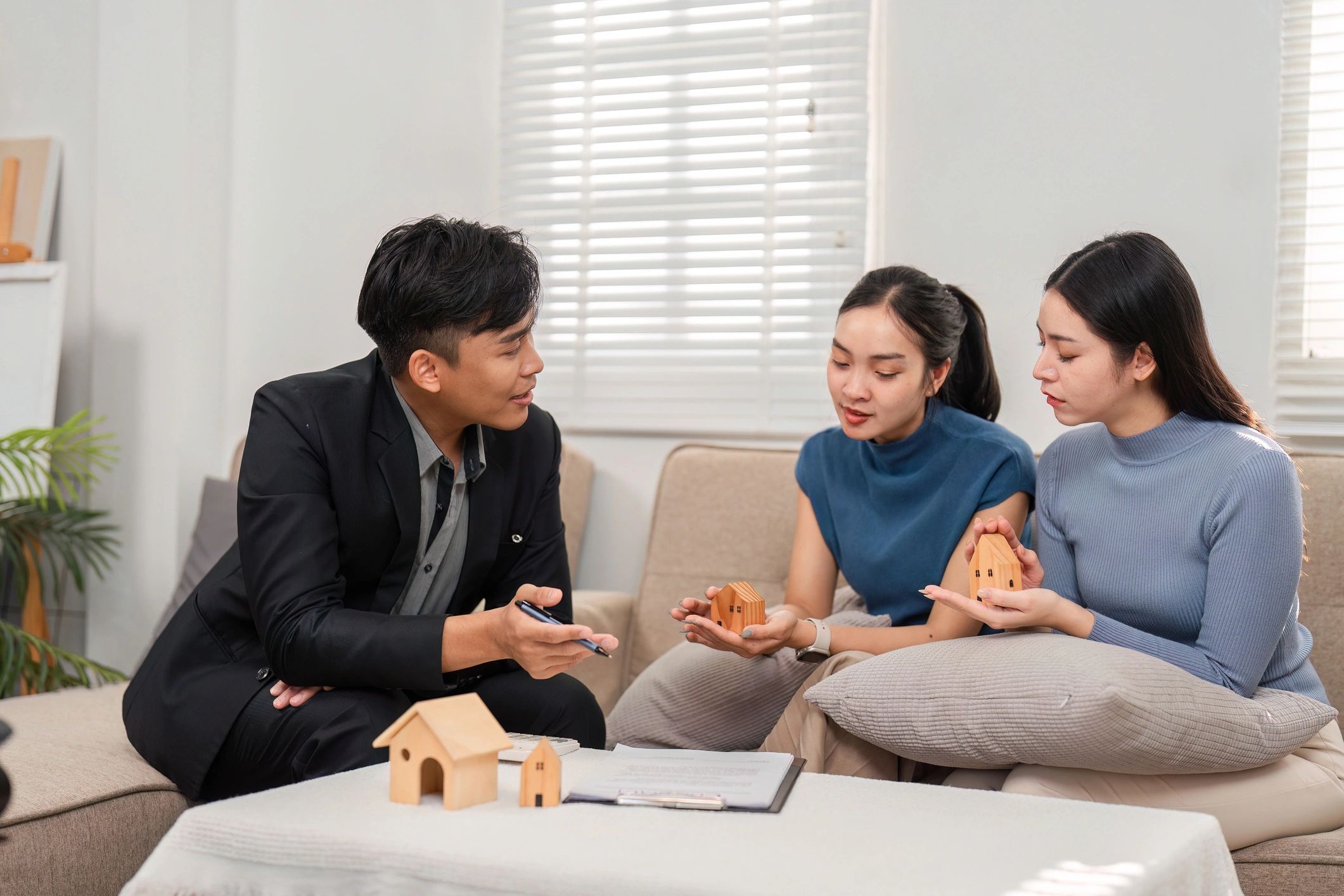 Couple discussing home plans with a real estate agent indoors.