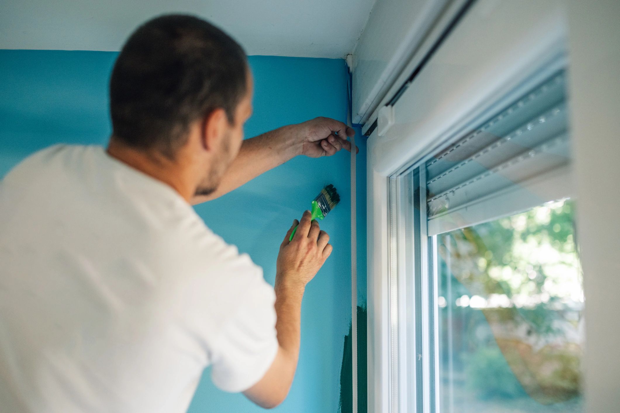 Man installing a window blind with a screwdriver.