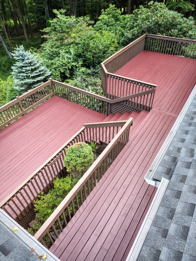 A large wooden deck with two sections overlooking a garden.