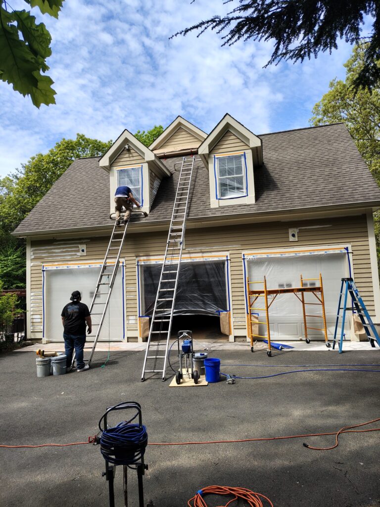 Workers repairing or painting the exterior of a two-story house.