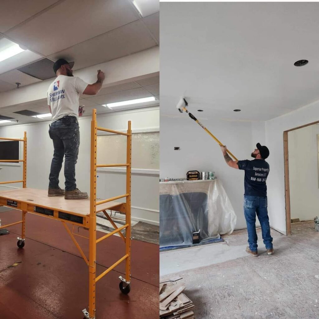 Two men working indoors, one on scaffolding and one using a selfie stick.
