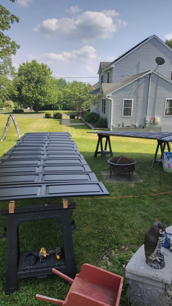 A painted door drying outdoors on sawhorses in a backyard.
