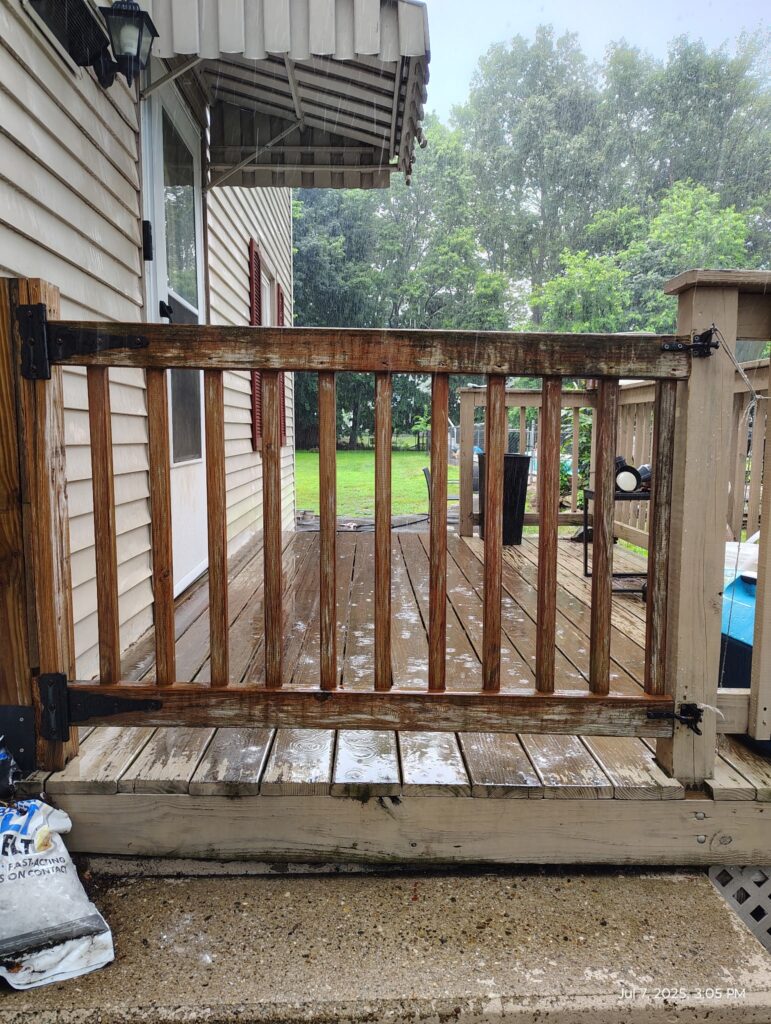 Wooden deck railing with vertical balusters on a rainy day.